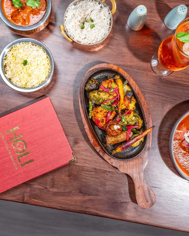 A sizzling platter set down beside the Holi menu
